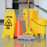 Wet Floor Sign With Mop Caution sign with mop and bucket on office floor